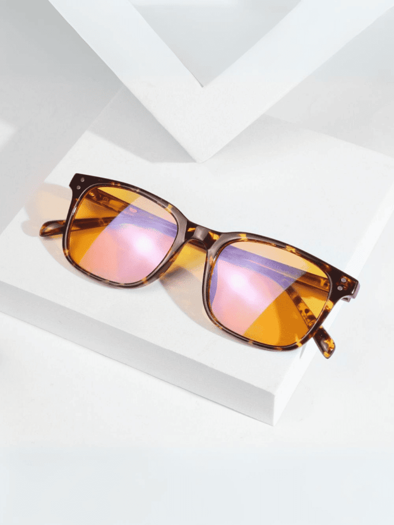Braune Sonnenbrille im Schildpattmuster mit orange-rosa Spiegelgläsern und eckigem Gestell auf weißen geometrischen Blöcken