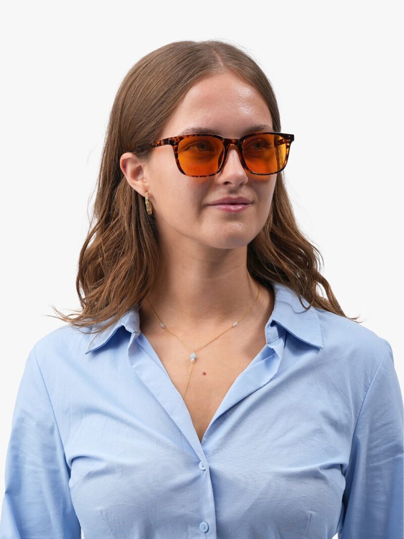 Frau mit der braunen Obsidian 90 Brille mit orangefarbenen Gläsern, hellblauem Hemd und goldenem Schmuck