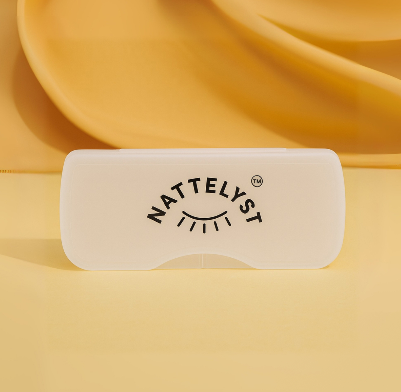 Transparent-weißes Etui mit NATTELYST-Logo auf warmgelbem Hintergrund